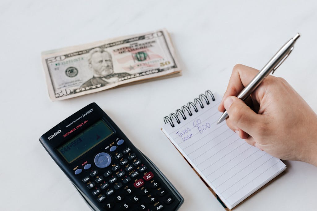 Photo by Photo By: Kaboompics.com Close-up of budgeting items including calculator, cash, and notebook for financial planning.