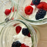 funfetti pudding cups with whipped cream, raspberries, blackberries on top