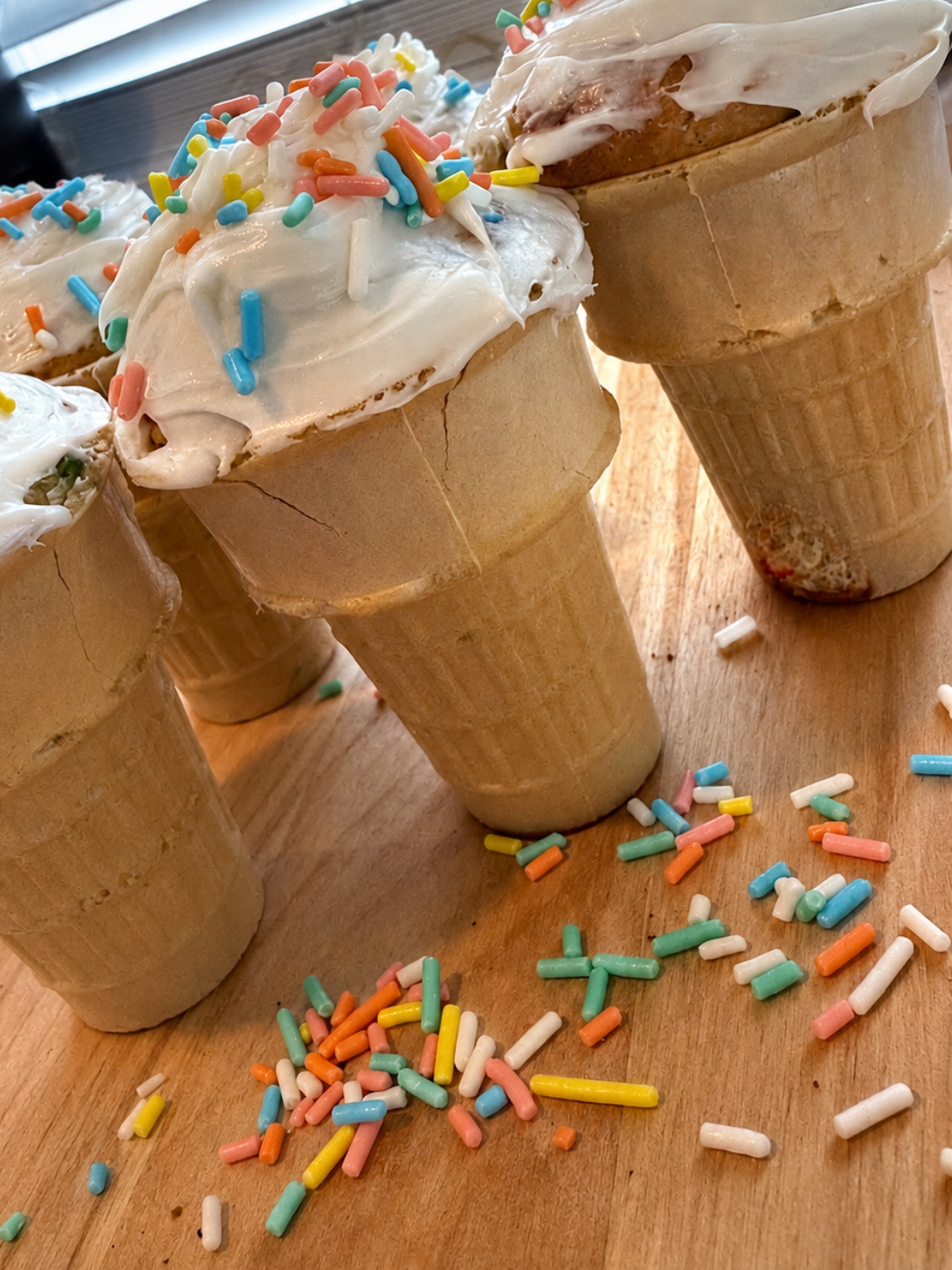 icecream cone cupcakes with white icing and multi colored sprinkles